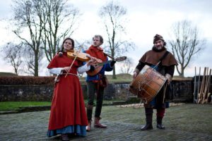 twee mannen en een vrouw in middeleeuws kleding met instrumenten